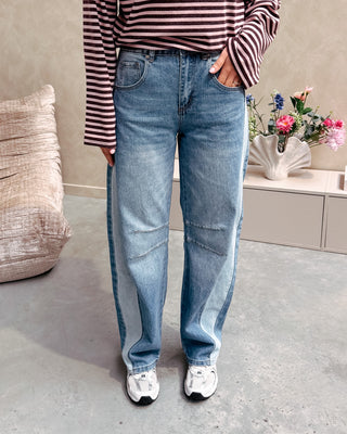 Model draagt een barrel jeansbroek met aan de zijkant een lichtere streep.