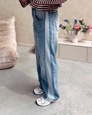 Model draagt een barrel jeansbroek met aan de zijkant een lichtere streep.