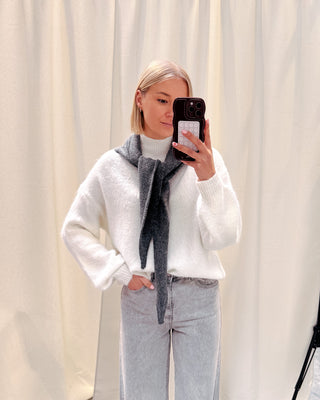 Model draagt een witte basic trui met daarop een donkergrijze driehoek sjaal.