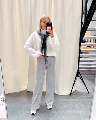 Model draagt een witte basic trui met daarop een donkergrijze driehoek sjaal.