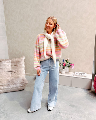 Model draagt een trui met pastel kleurtjes en daarop een ecru driehoek sjaal.