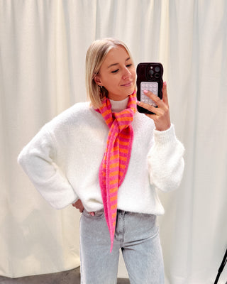 Model draagt een witte basic trui met daarop een driehoek sjaaltje met streepjes in felle kleurtjes, oranje en roze.
